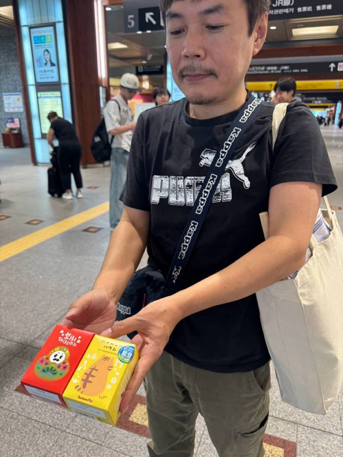 金沢駅構内でお土産を手に立つ男性