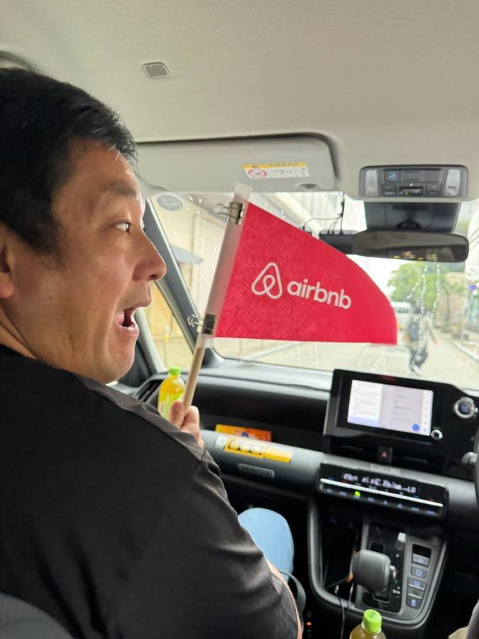 車内でAirbnbの旗を振る男性