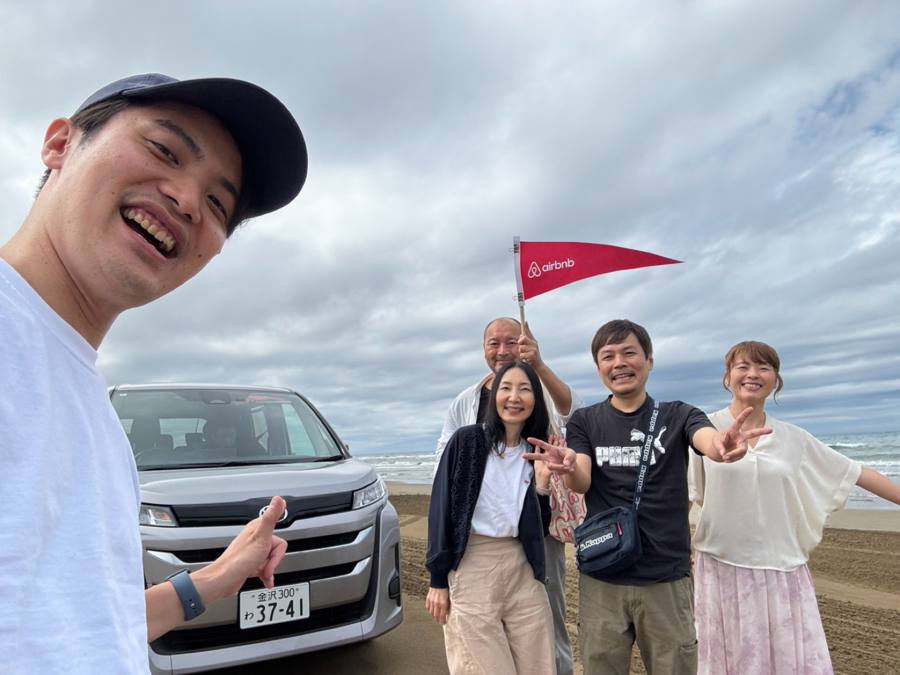 車前で笑う5人のグループ写真