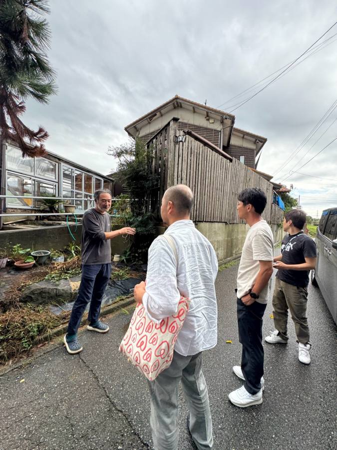 民宿前で家主と話す4人