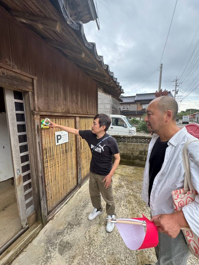古民家前で表示物を指し話す2人
