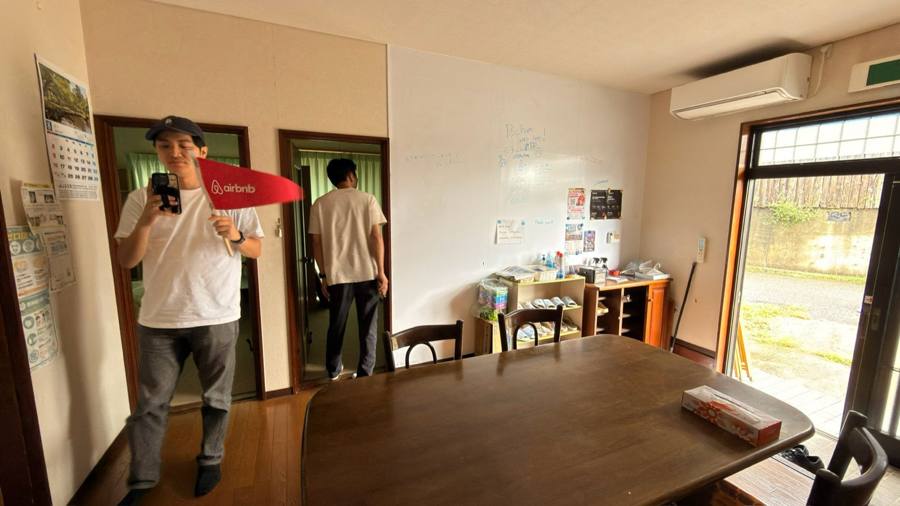 民宿の部屋で旗を持ち自撮りする男性