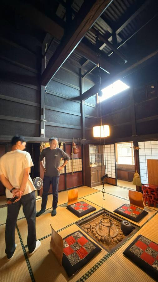 囲炉裏の前で説明を聞く二人