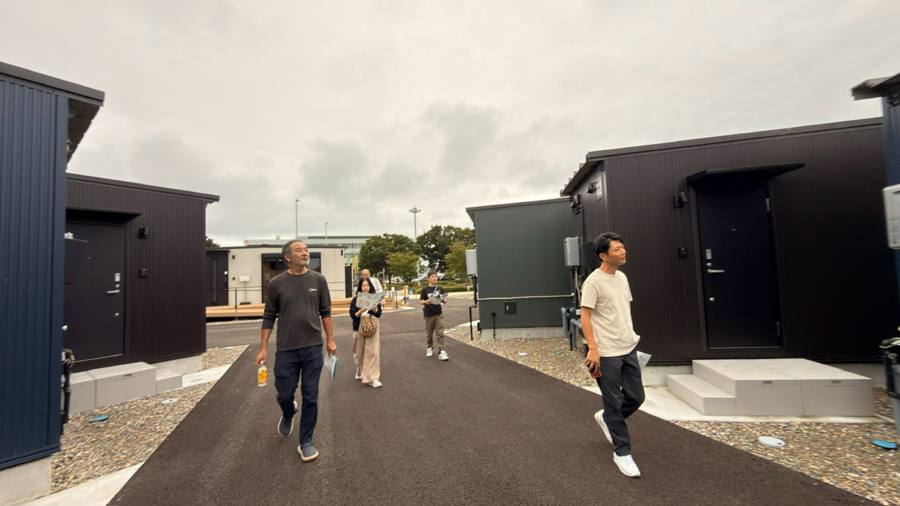 仮設住宅の敷地内を歩く一同